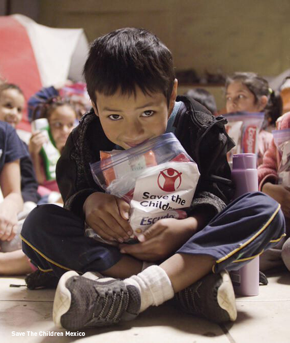 A child smiles while holding a care package