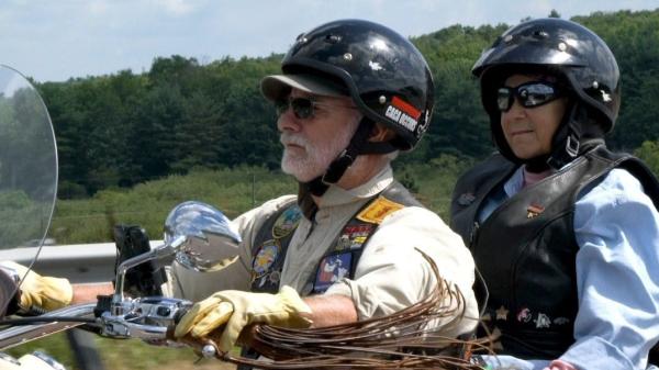 Two people enjoy a motorcycle ride on a sunny day